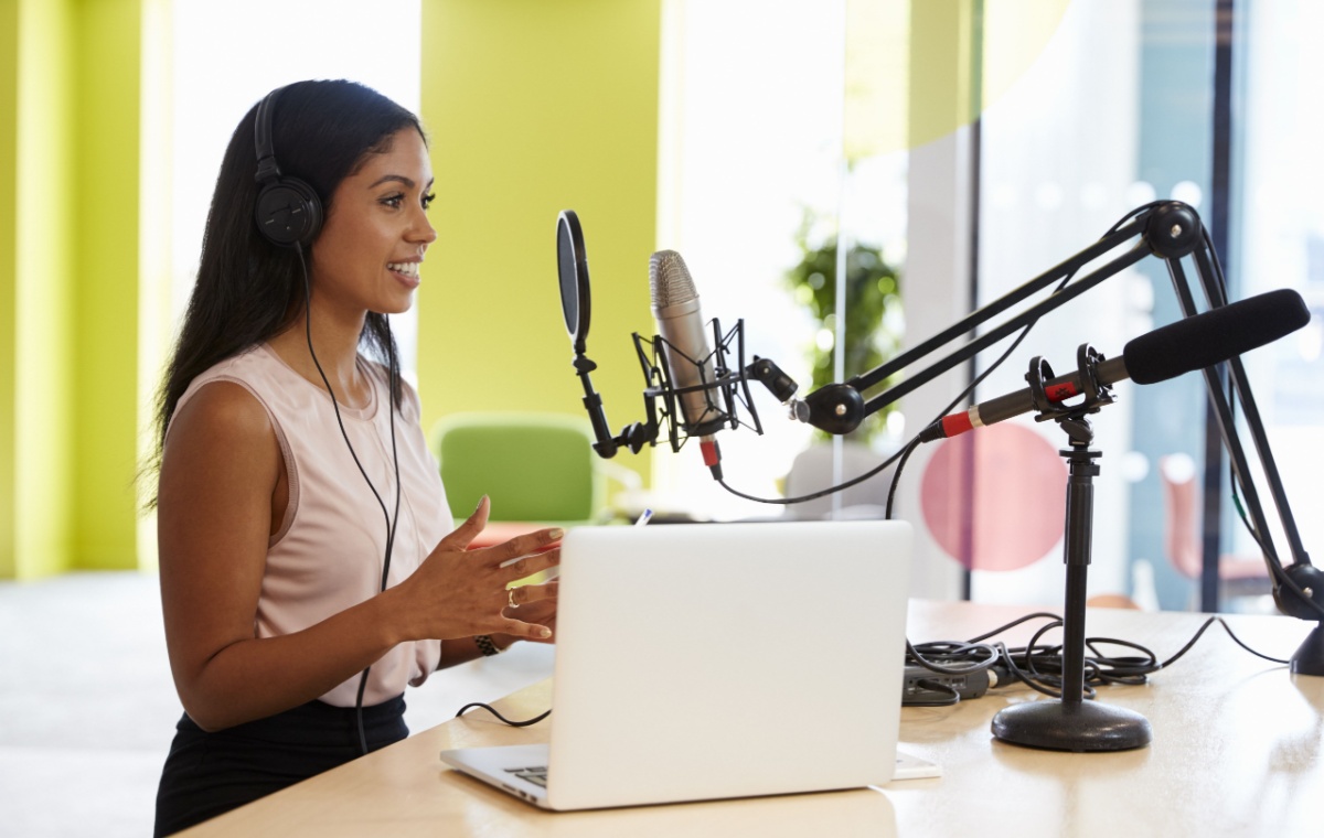 Woman speakinginto a podcasting microphone - a b2b content marketing trend