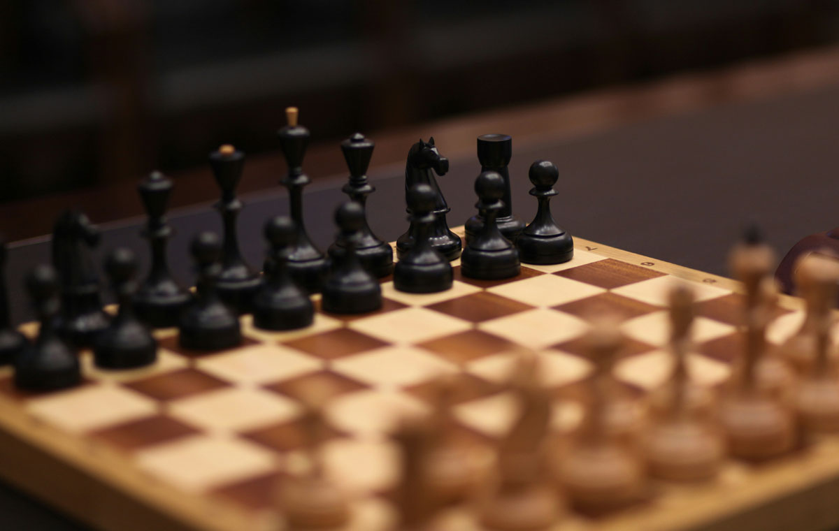 A wooden chess board with dark and light pieces