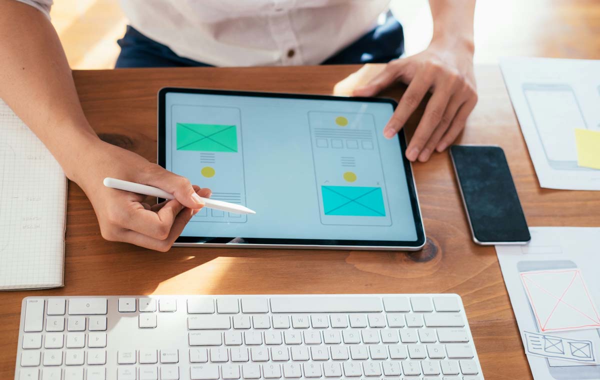 A woman works on a website refresh with a wireframe design at a desk.